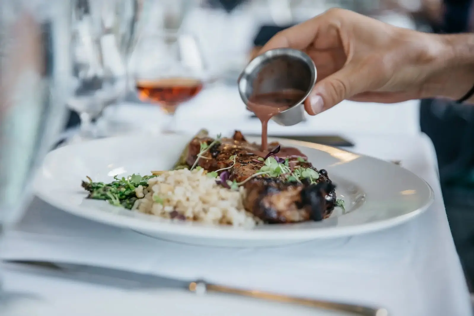 pouring sauce over plate of food